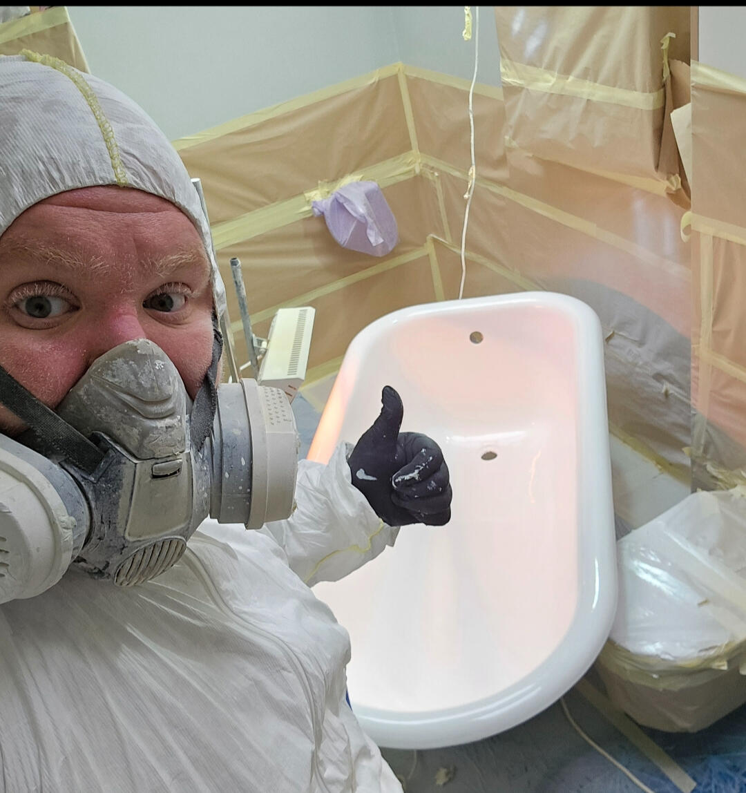 photo of glossy baths owner photo of glossy baths re-enamelling owner Seamus with a thumbs up, in ppe, in a room full of masking up and a completed bath in Gloucester
